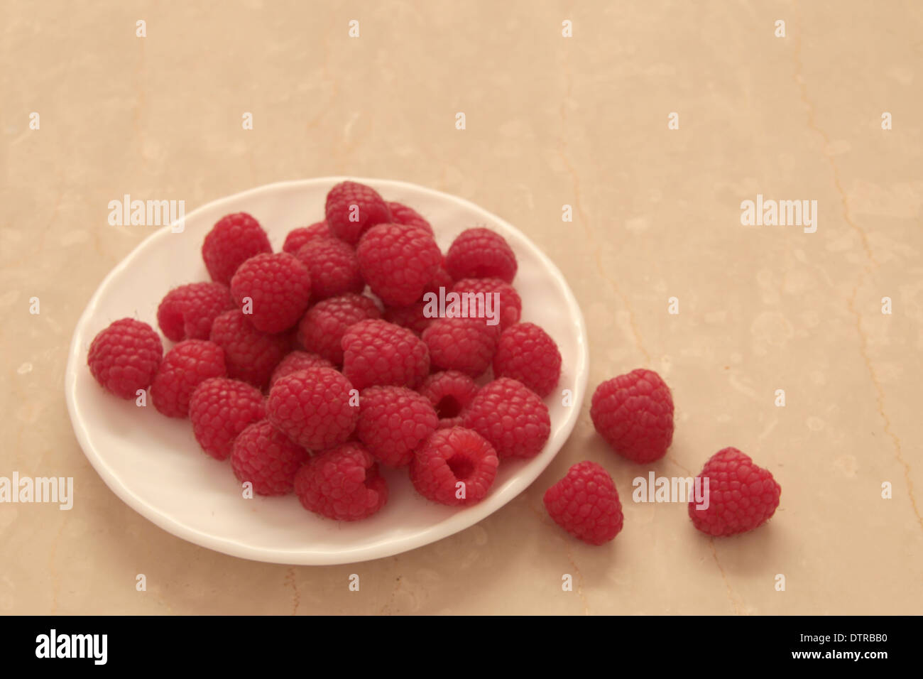 Lamponi su una piastra bianca con 3 raspe a lato la crema su un sfondo marmo (7 di 11) Foto Stock