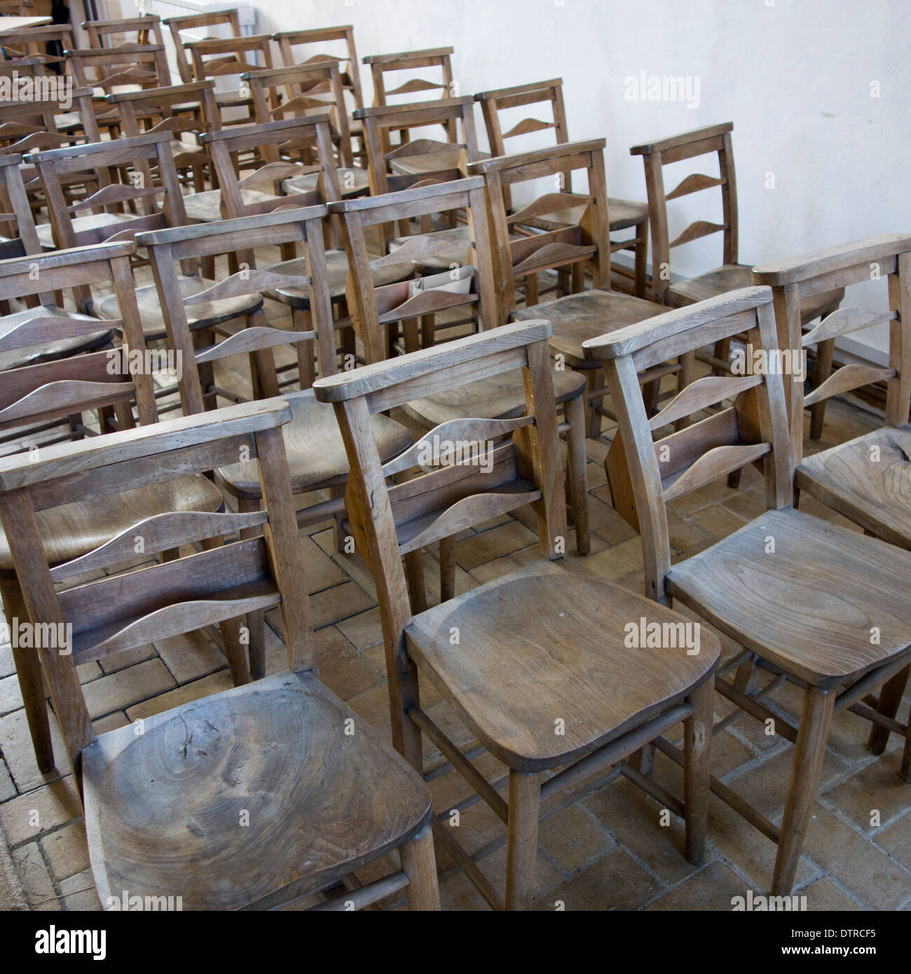 Seduti comodamente: le righe di legno duro di sedi allineate in una chiesa. Foto Stock