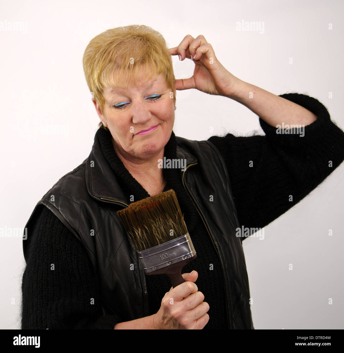 Capelli biondi donna che guarda perplesso con spazzola di vernice Foto Stock