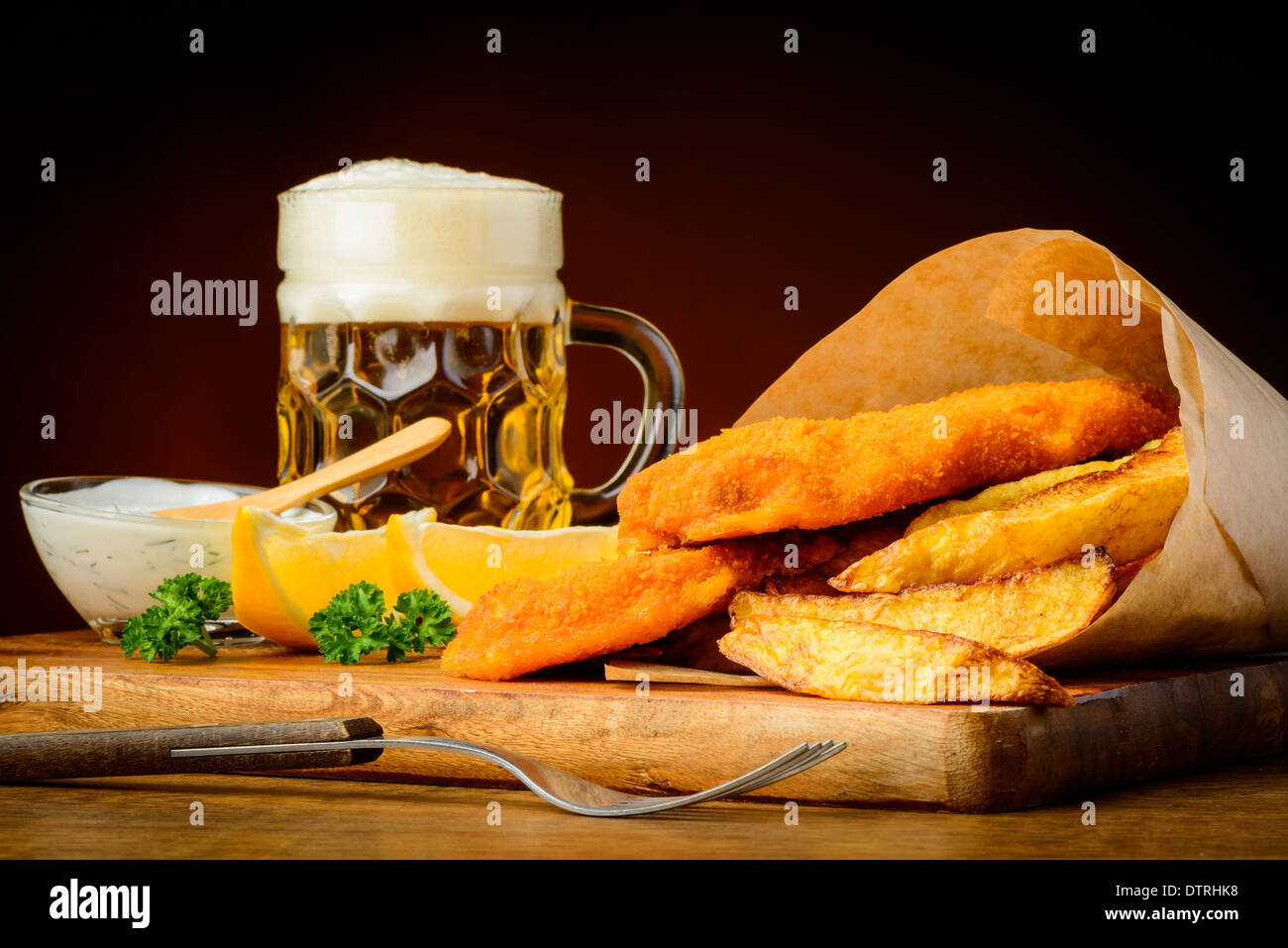 Il tradizionale pesce e patatine menu con un bicchiere di birra Foto Stock