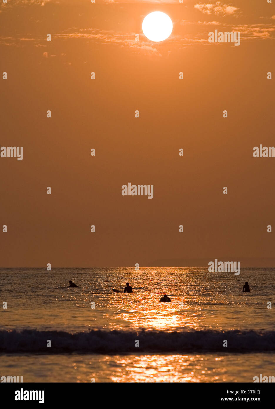 Surfer al tramonto in spiaggia di Devon Foto Stock