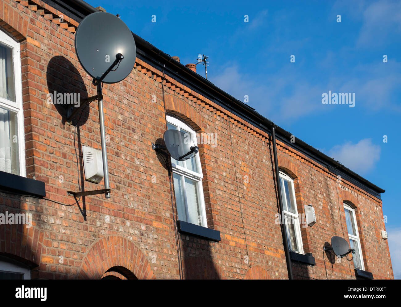 Antenne satellitari su una fila di case a schiera a Manchester in Inghilterra, Regno Unito Foto Stock