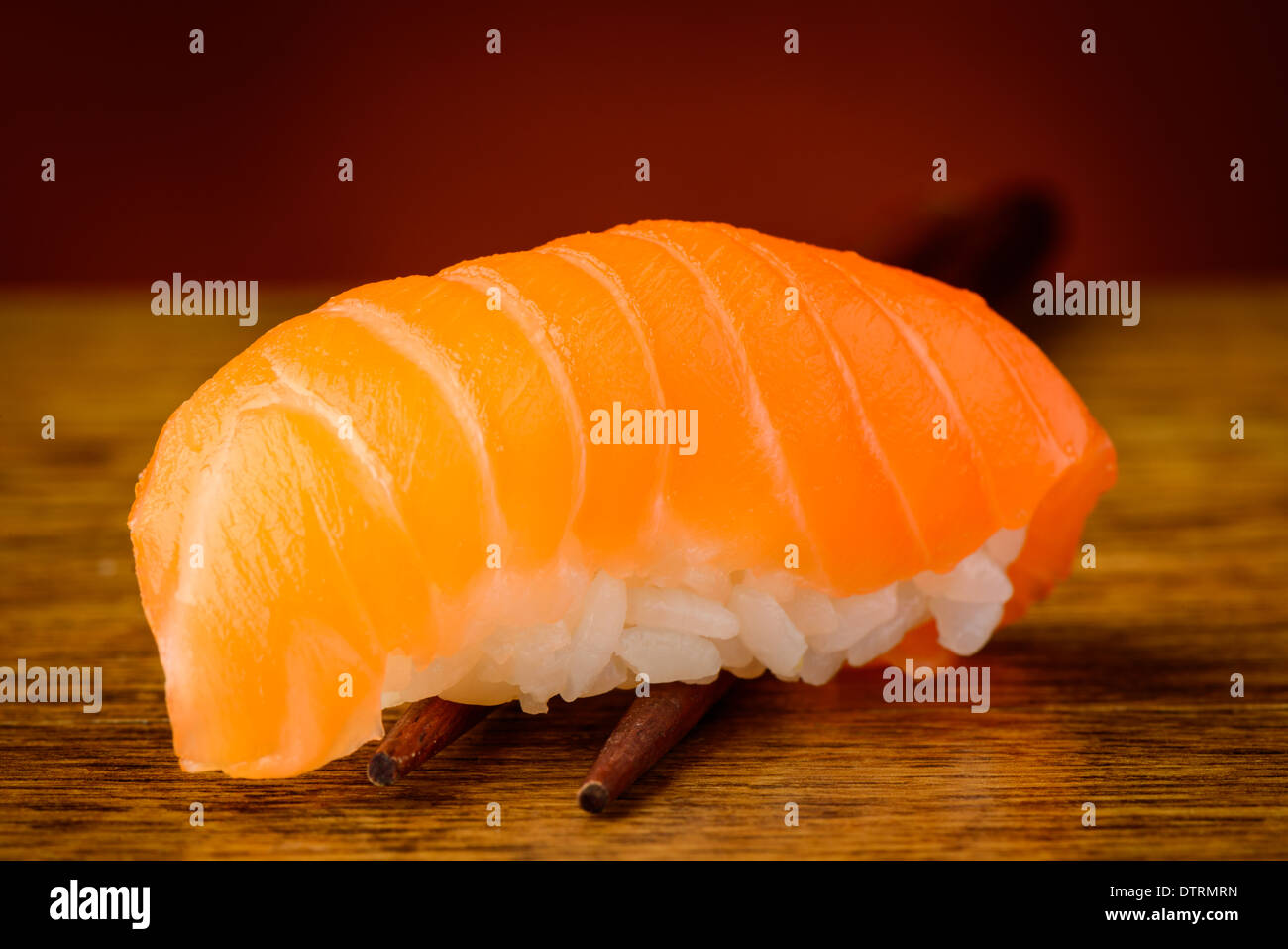 Primo piano particolare di nigiri sushi con salmone su bacchette Foto Stock