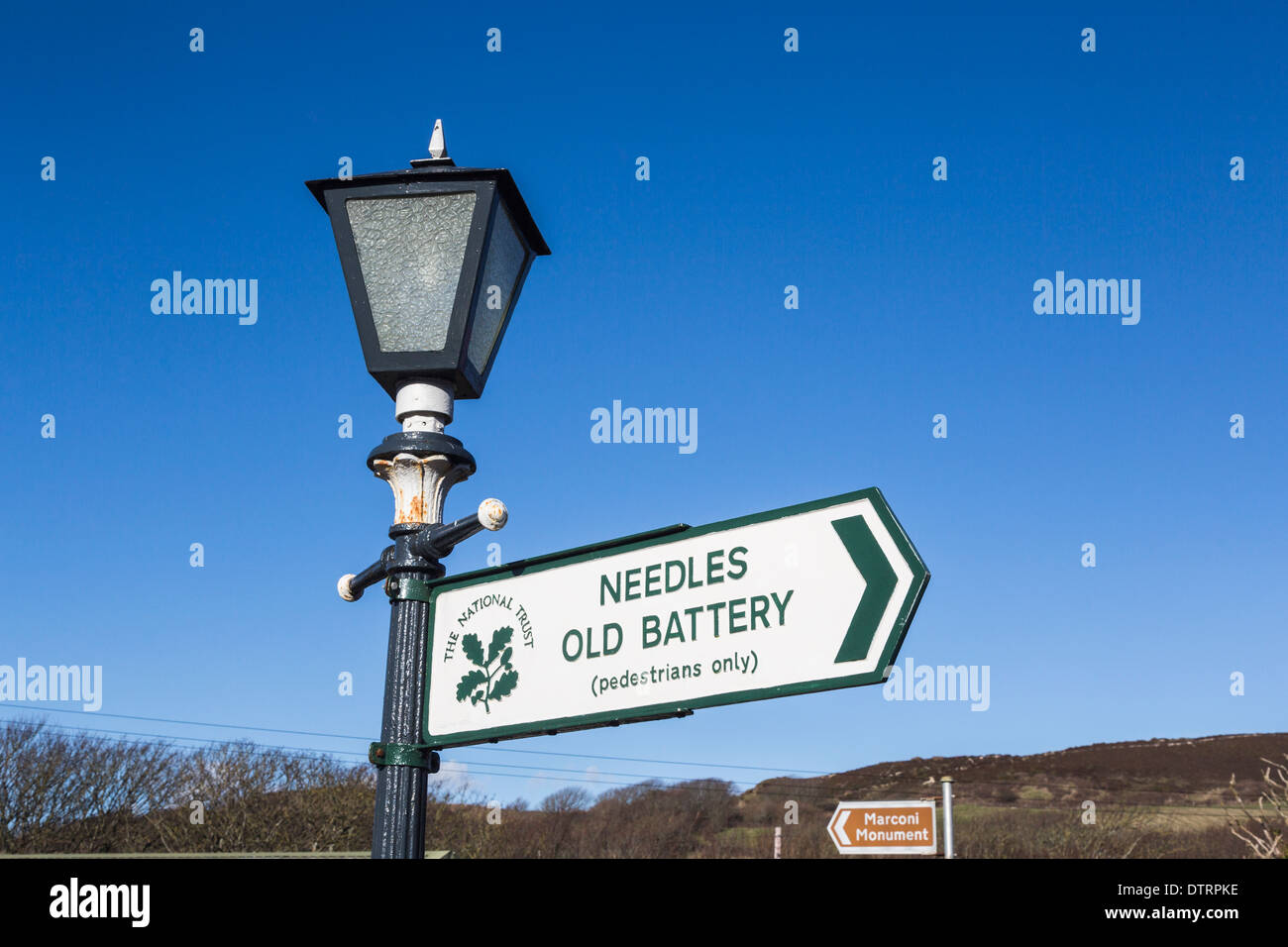 Il National Trust segno sulla lampada posta in corrispondenza degli aghi Country Park, Isle of Wight, rivolta verso gli aghi e la vecchia batteria Foto Stock