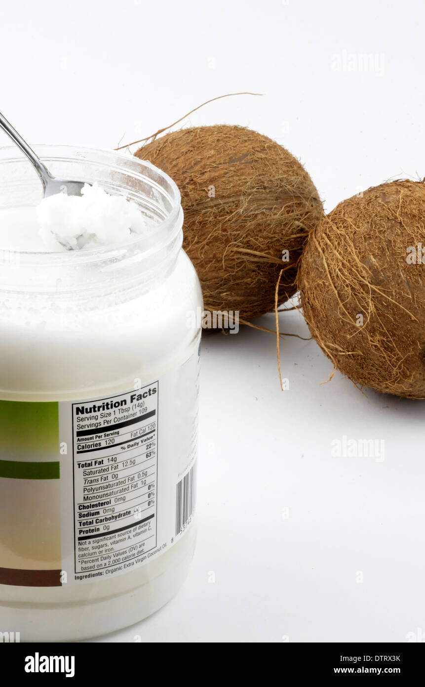 Fatti di nutrizione etichetta su olio di noce di cocco contenitore mostrato con due noci di cocco. Foto Stock