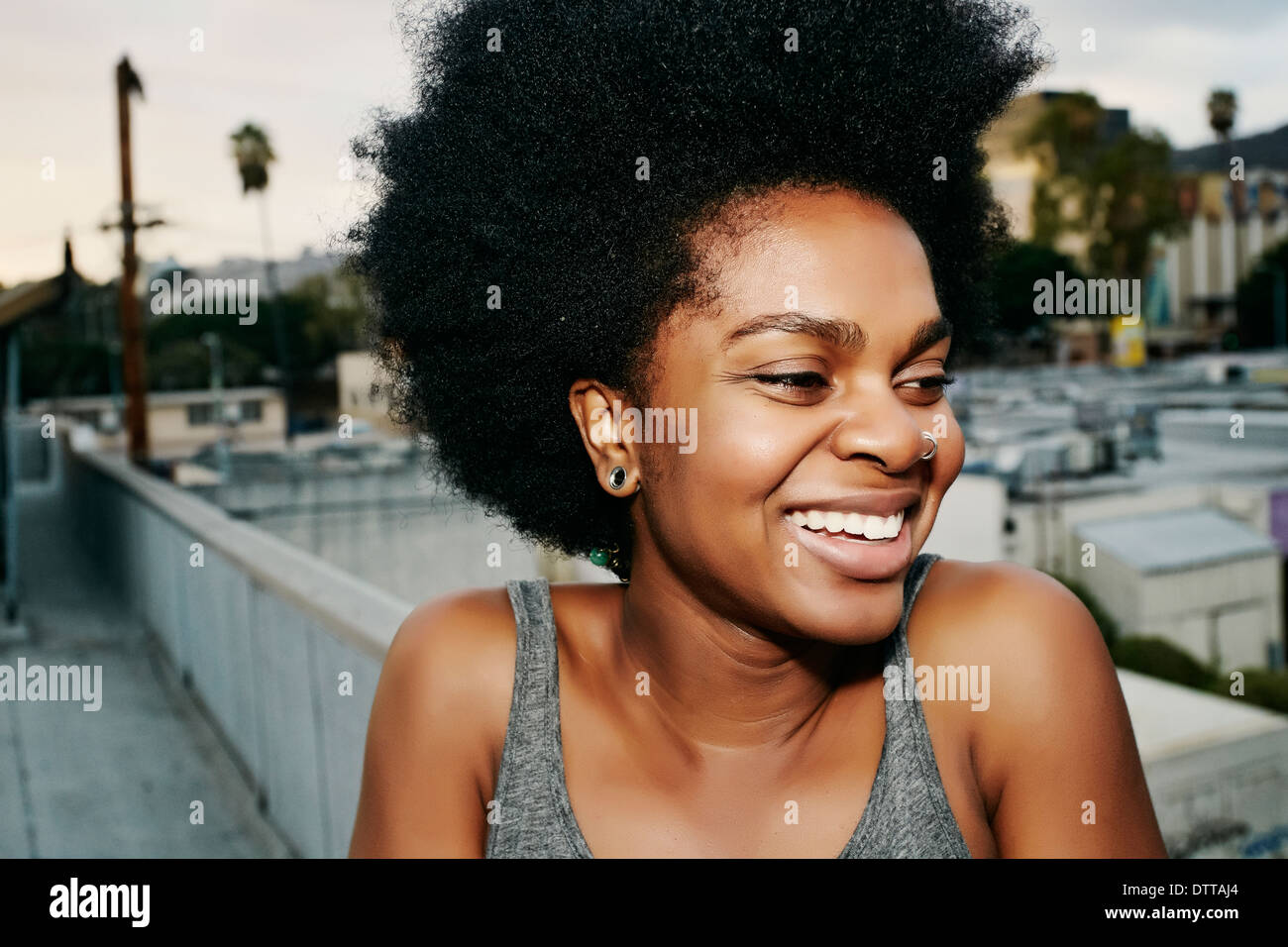 Nero donna sorridente sul tetto urbano Foto Stock