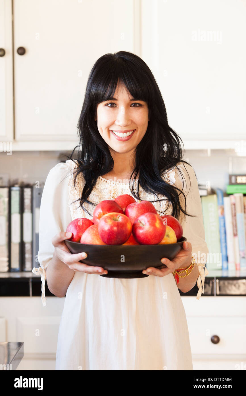 Donna che mantiene una cesta di frutta in cucina Foto Stock