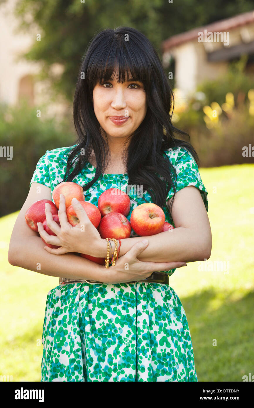 Donna che mantiene armfuls di frutta Foto Stock