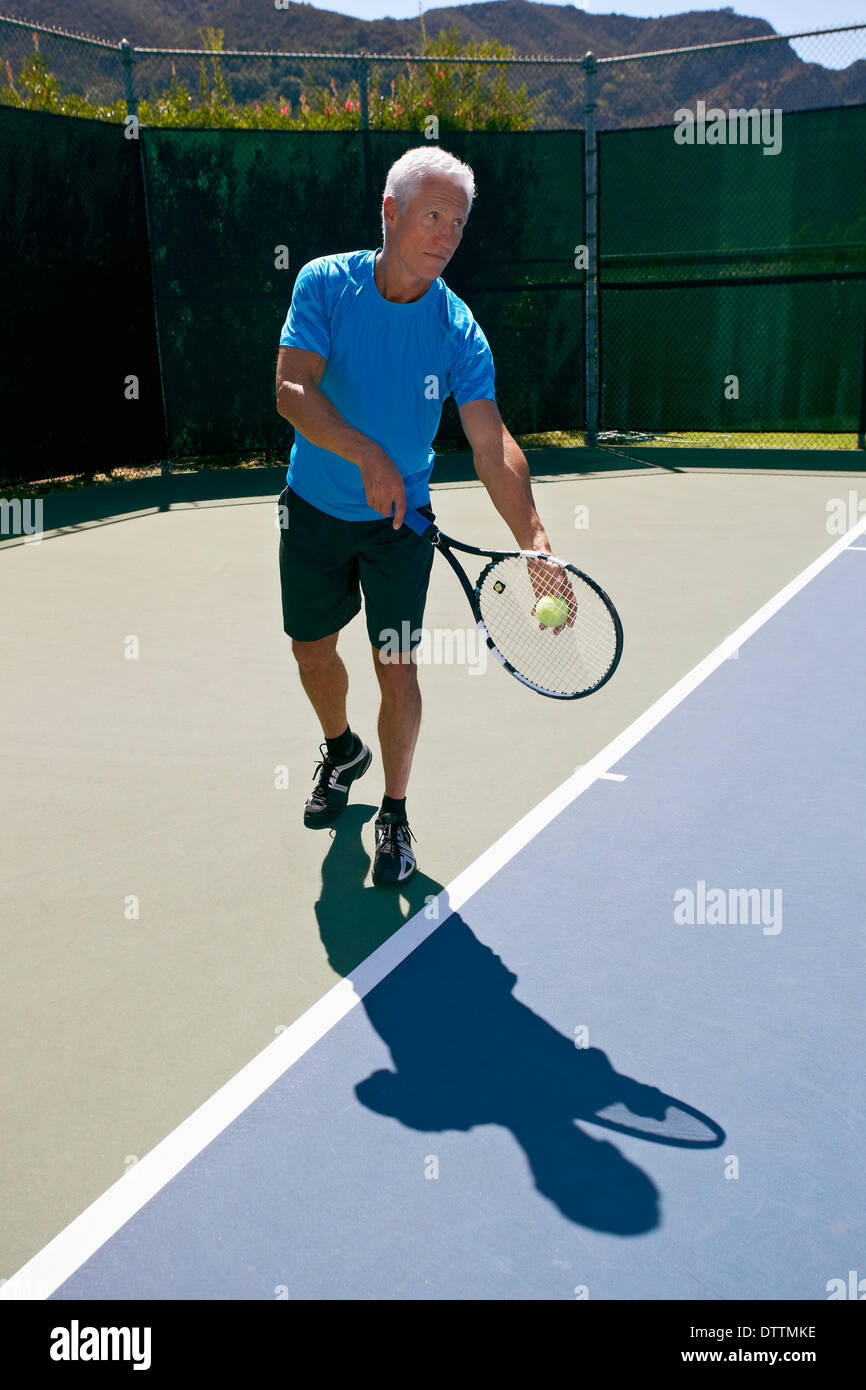 Uomo caucasico giocando a tennis su corte Foto Stock