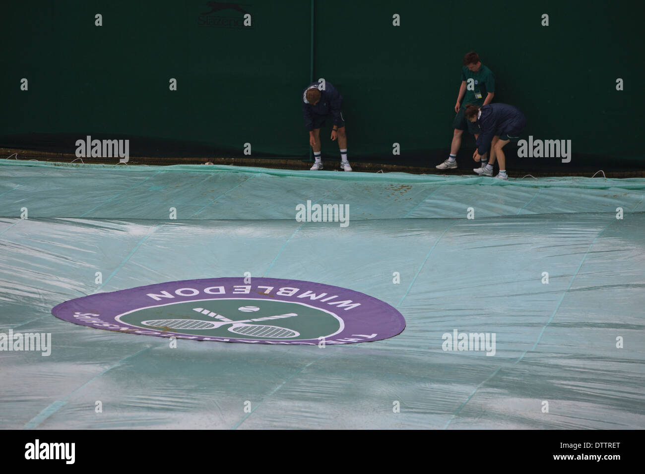 Wimbledon Tennis Championship corte coperchio con tre groundsman sotto la pioggia Foto Stock