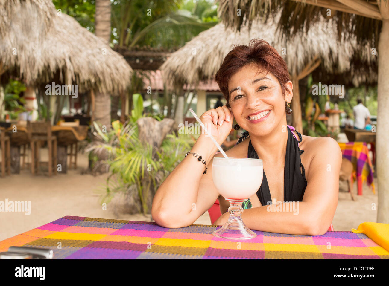 Donna ispanica godendo tropical drink al resort Foto Stock