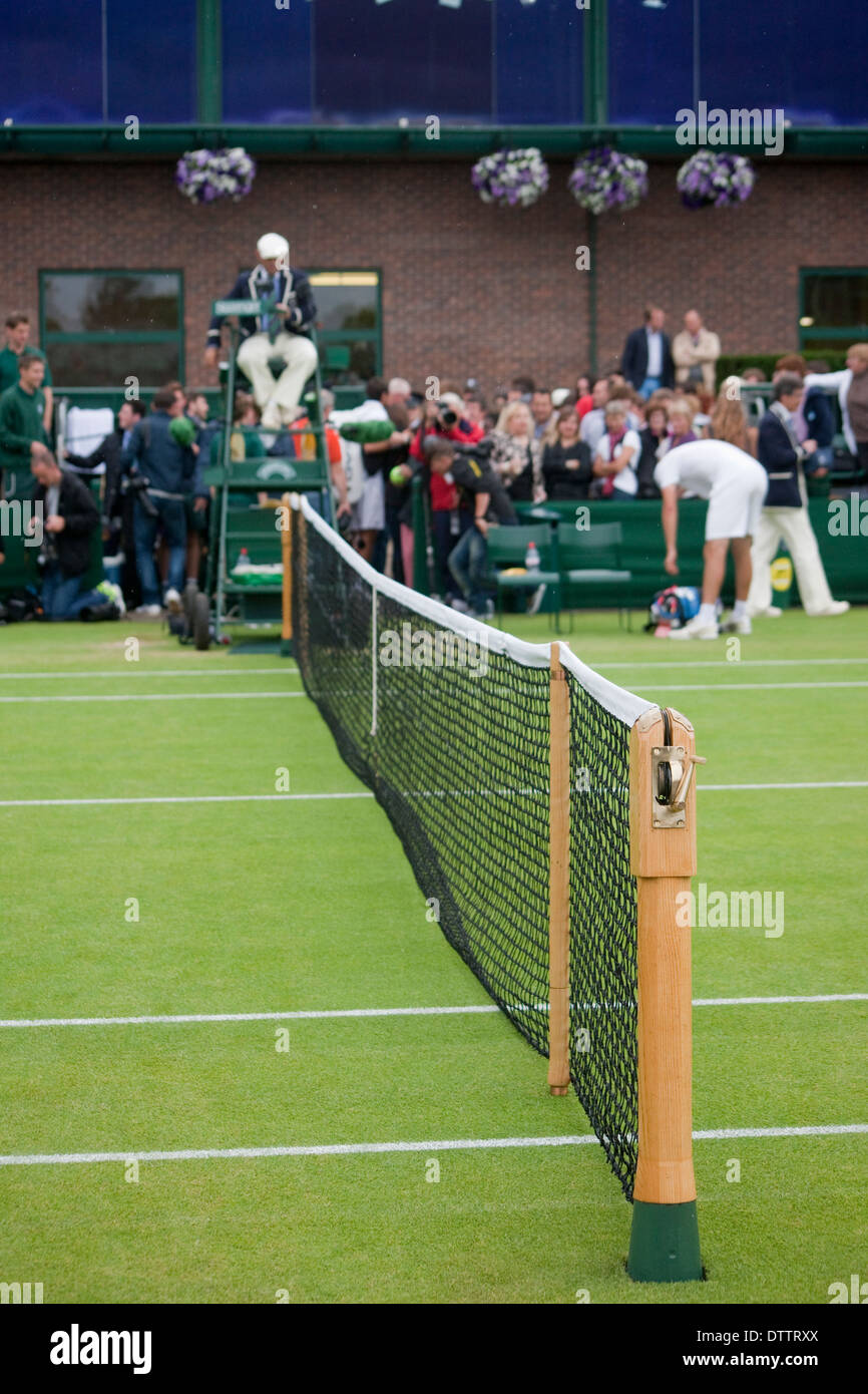 Wimbledon Tennis net ,in primo piano, con folla arbitro e giocatore al di fuori della messa a fuoco in background Foto Stock