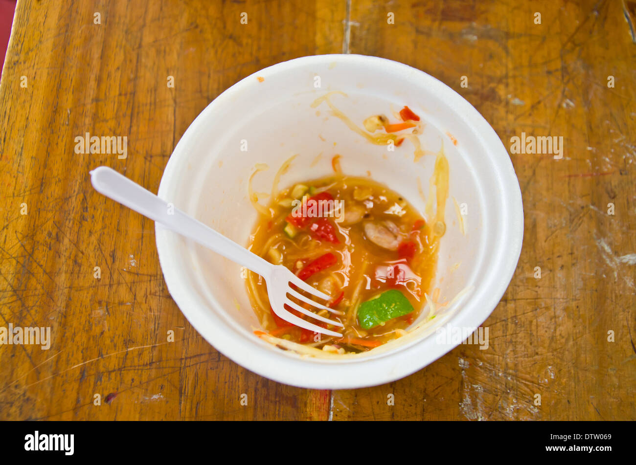 La coppa di plastica e lo spreco di cibo su uno sfondo di legno Foto Stock