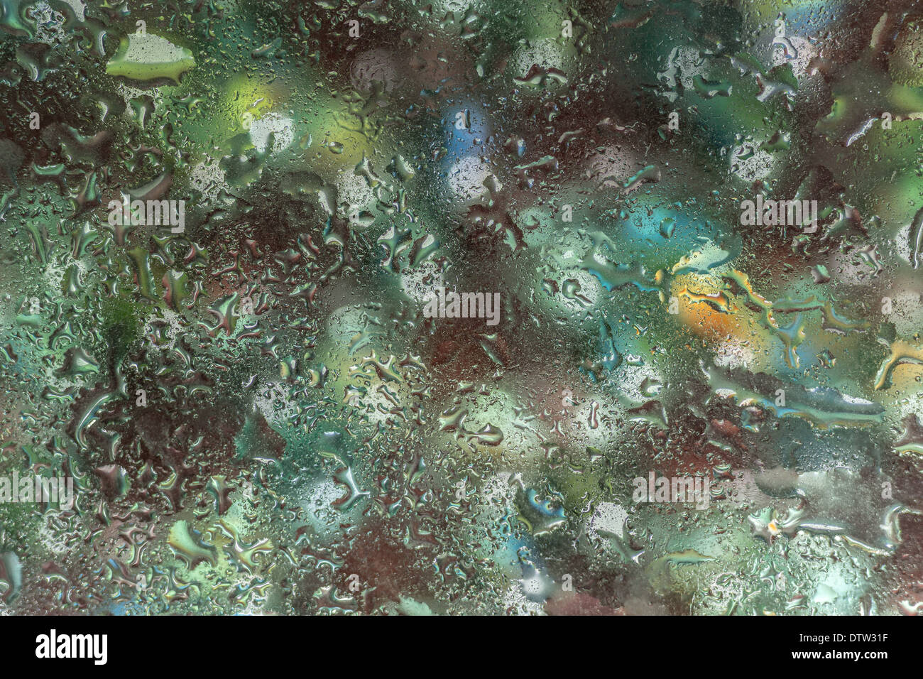 Una luminosa colorata immagine di sfondo di goccioline di acqua su una superficie di vetro Foto Stock