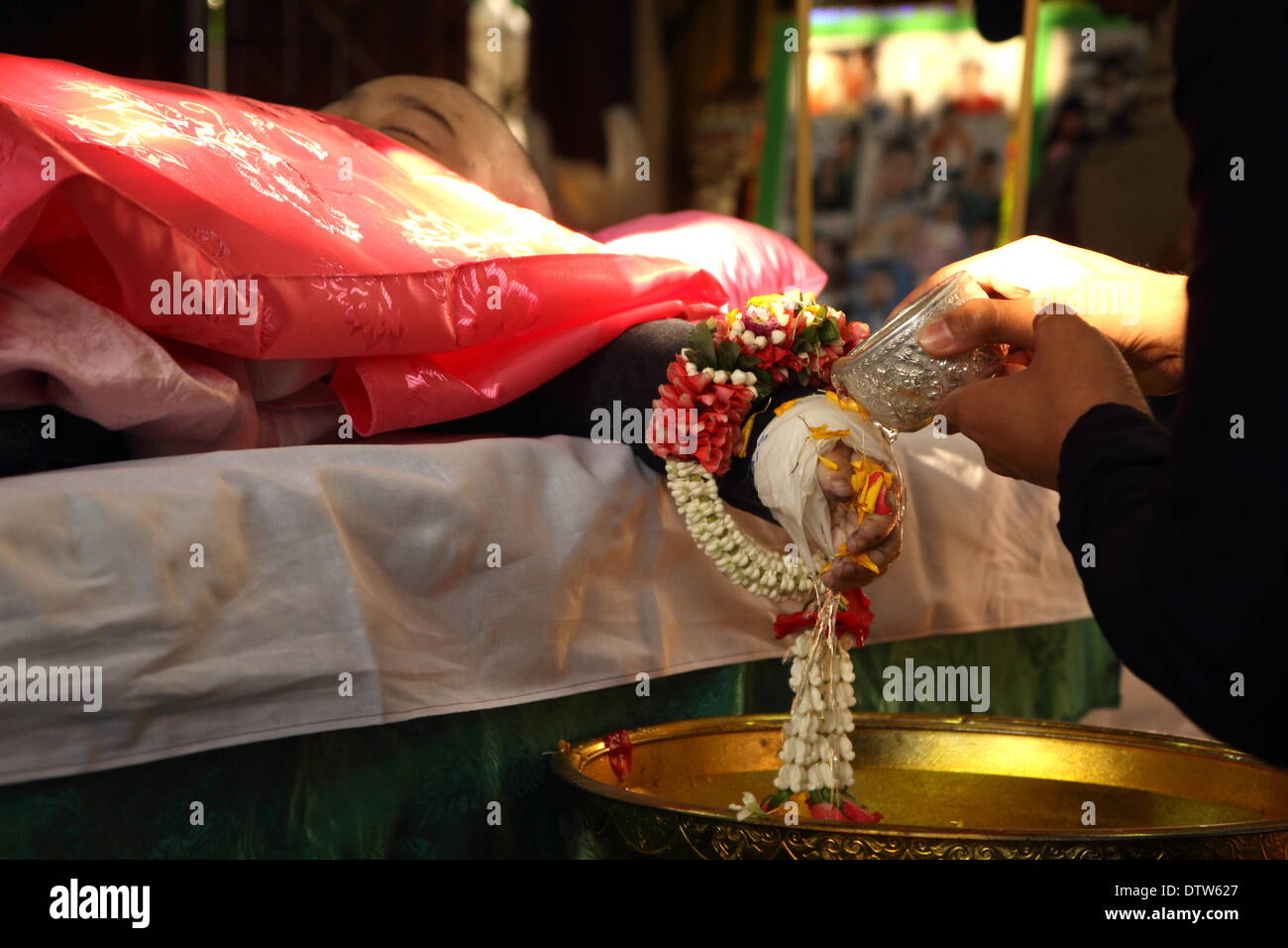 Bangkok, Tailandia. 24 Febbraio, 2014. La gente si riversa l'acqua sulle mani del corpo di 6-year-old Patcharakorn Yosubon vittima di un attentato, durante gli ultimi riti eseguita presso un tempio buddista. Due giovani fratelli, 6-anno-vecchia ragazza Patcharakorn e il suo 4-anno-vecchio fratello Korawit, insieme con un'altra donna sono stati uccisi uccidendo almeno 22 persone in un attacco granata contro il governo anti-manifestanti nel quartiere dello shopping a Bangkok. Credito: John Vincent/Alamy Live News Foto Stock