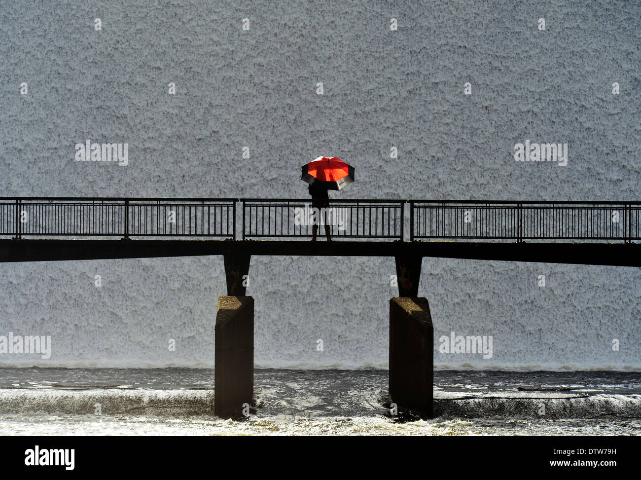 Serbatoio Sleddale, Cumbria, Regno Unito. 24 Febbraio, 2014. Un viandante attraversa il ponte come un muro di cascate di acqua sopra la diga del gonfio Wet Sleddale serbatoio nel fiume Lowther vicino a Shap, Cumbria. Cumbria ha ricevuto quasi un mese vale la pena di pioggia su domenica e lunedì. Wet Sleddale è un nome adatto per la quantità di pioggia riceve ed era la posizione per il film di culto Withnail ed io con molte delle scene riprese sotto la pioggia battente Credito: Stuart Walker Fotografia/Alamy Live News Foto Stock