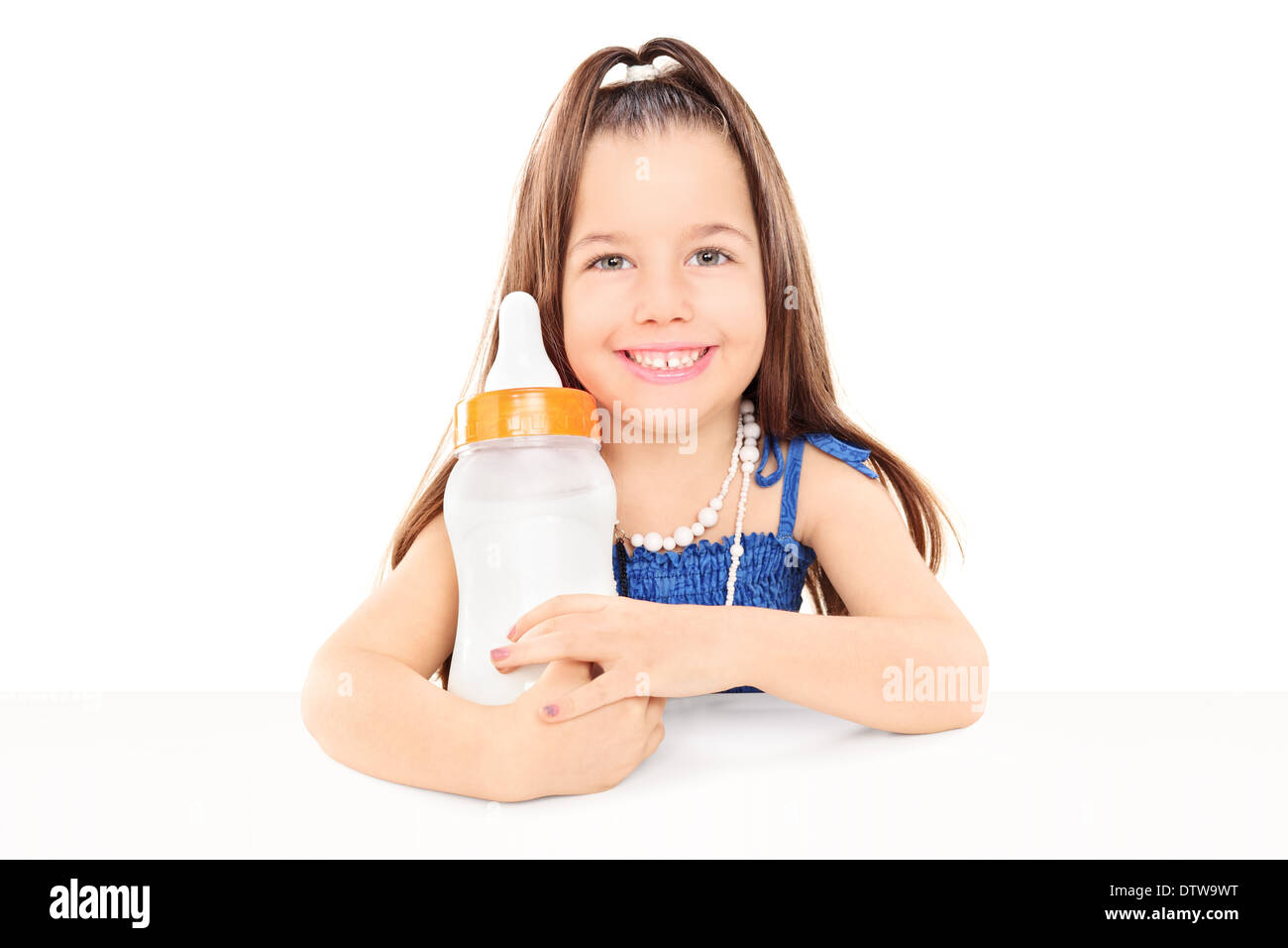 Eleganti bambina tenendo un enorme bottiglia bambino seduto a tavola Foto Stock