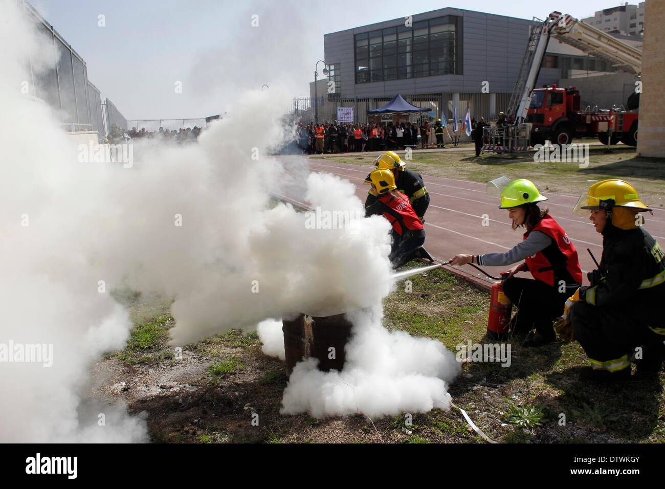 (140224) -- Gerusalemme, Feb 24, 2014 (Xinhua) -- soccorritori guidano gli studenti per estinguere un incendio durante un trapano di difesa al Ulpana Bnei Akiva la scuola per ragazze di Pisgat Ze'ev, Gerusalemme est, nel febbraio 24, 2014. Istruzione israeliano Ministero, insieme con Forze di Difesa Israeliane (IDF) Homefront comando, le autorità locali, la polizia e la Magen David Adam (MDA) come pure il fuoco e forze di soccorso, terrà una nazione a livello di difesa del trapano, compresi evacuazione feriti studenti, estinzione di incendi e di preparazione per il razzo colpisce il lunedì per affinare le procedure in caso di emergenza per gli studenti da e Foto Stock