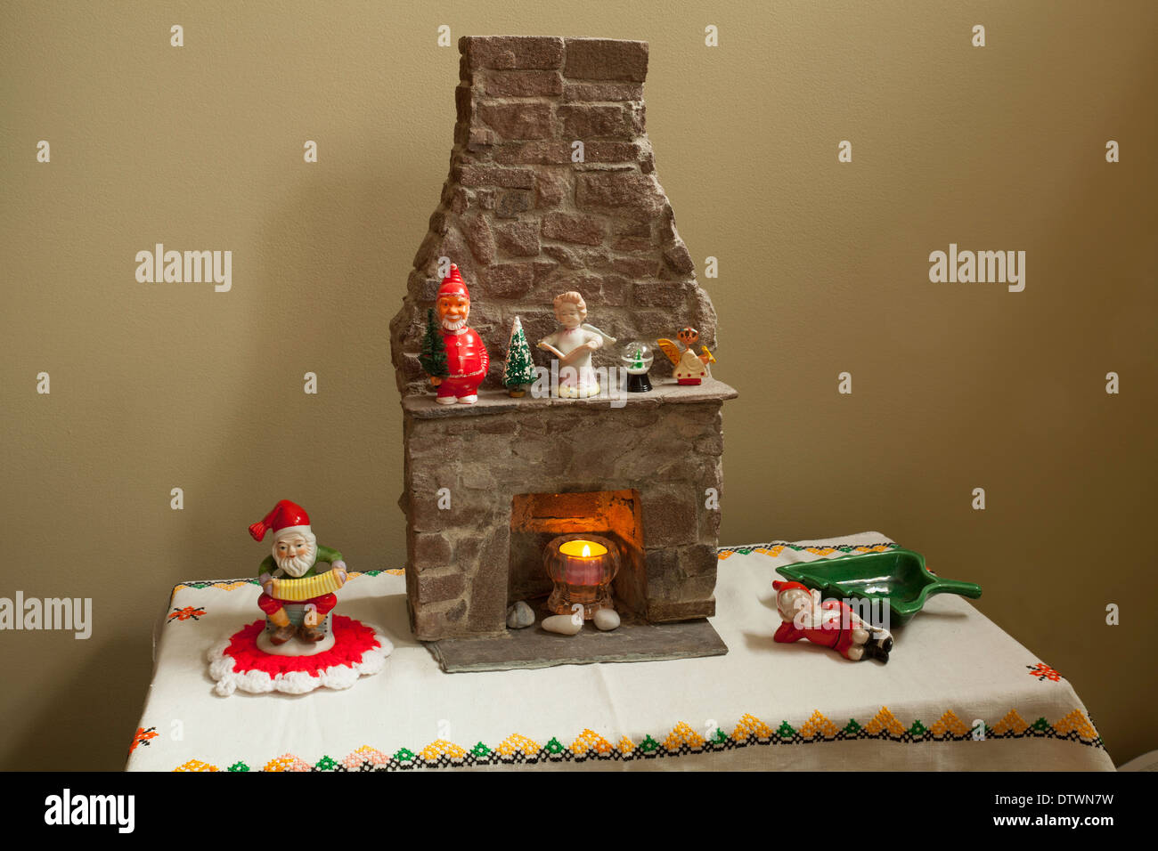 Un assortimento di decorazioni di Natale intorno a una miniatura del caminetto in pietra, compreso un vintage Santa bobble-testa sul mantello. Foto Stock