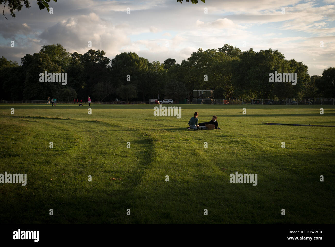 Una coppia avente una tarda sera picnic estivo sull'erba verde di un parco di Londra Foto Stock