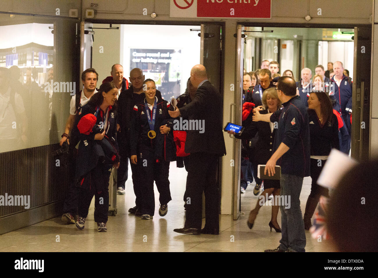 Aeroporto di Heathrow di Londra, Regno Unito. Il 24 febbraio 2014. Liz Yarnold vincitore della medaglia d oro di donne al suo scheletro event arriva a Heathrow airport seguita da membri del team di GB dal 2014 Olimpiadi invernali di Sochi indossando la sua medaglia d oro Credito: amer ghazzal/Alamy Live News Foto Stock