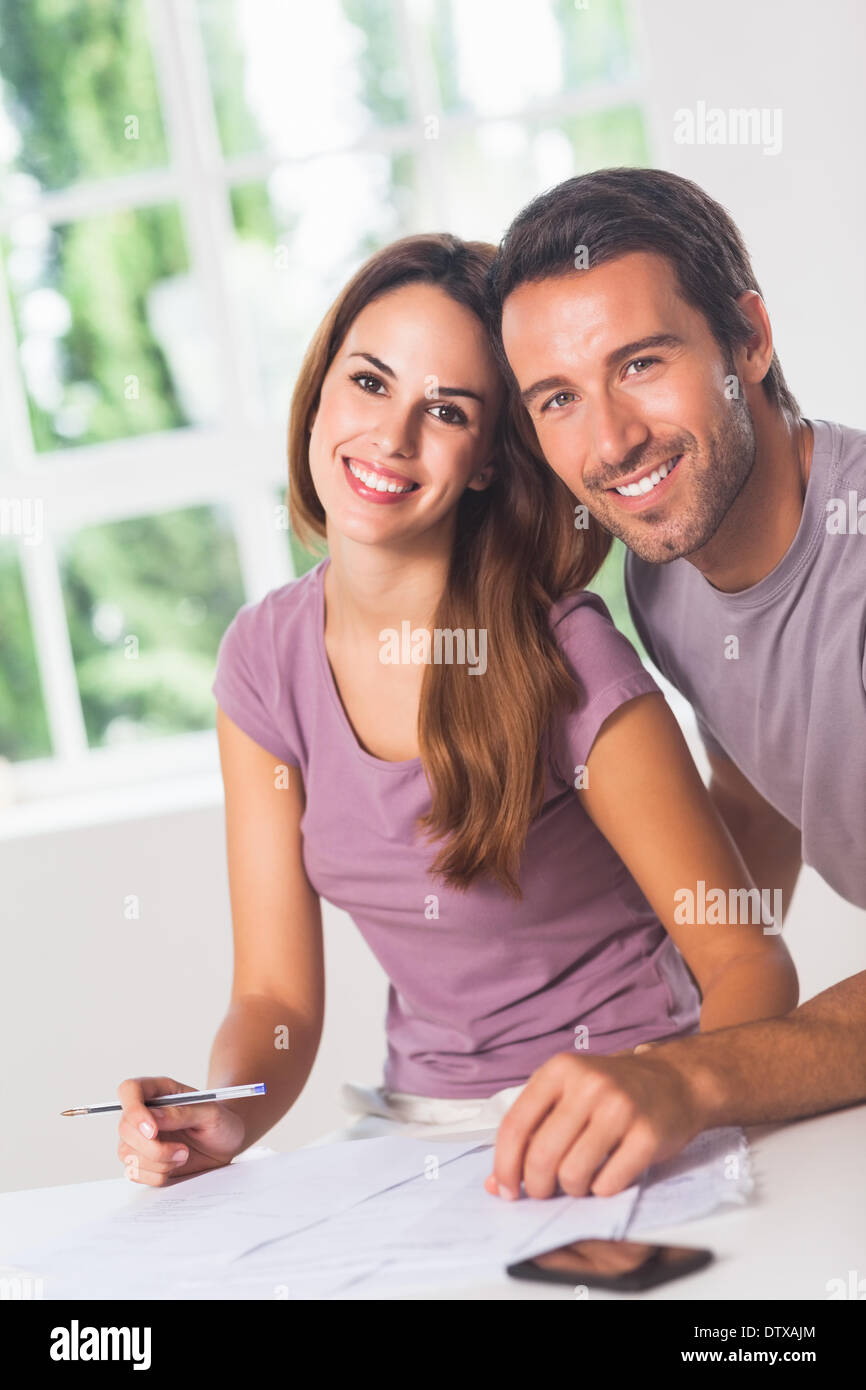 Coppia sorridente verso la telecamera con le fatture Foto Stock