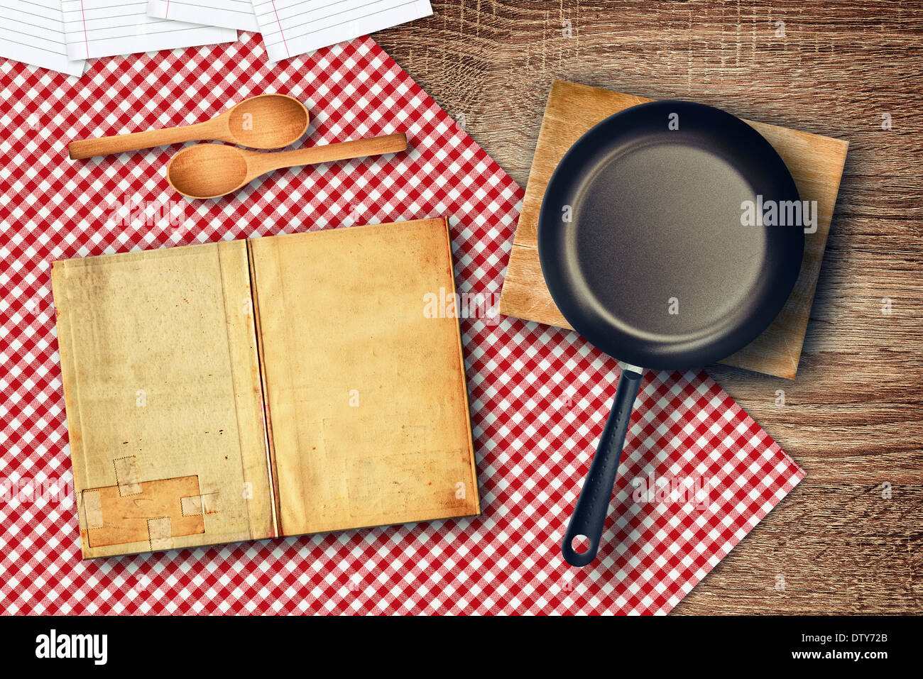 La preparazione del cibo sul tavolo della cucina. Vari utensili da cucina sul tavolo - cucchiai, libro di ricette e padella. Foto Stock