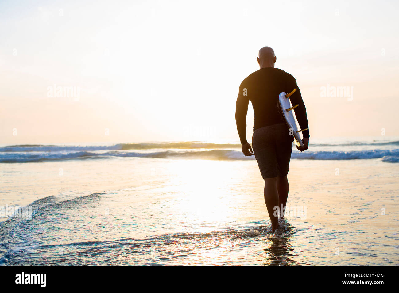 Razza mista uomo a camminare con la tavola da surf in spiaggia Foto Stock