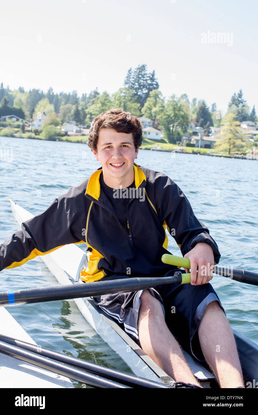 Razza mista ragazzo adolescente scull canottaggio sul lago Foto Stock