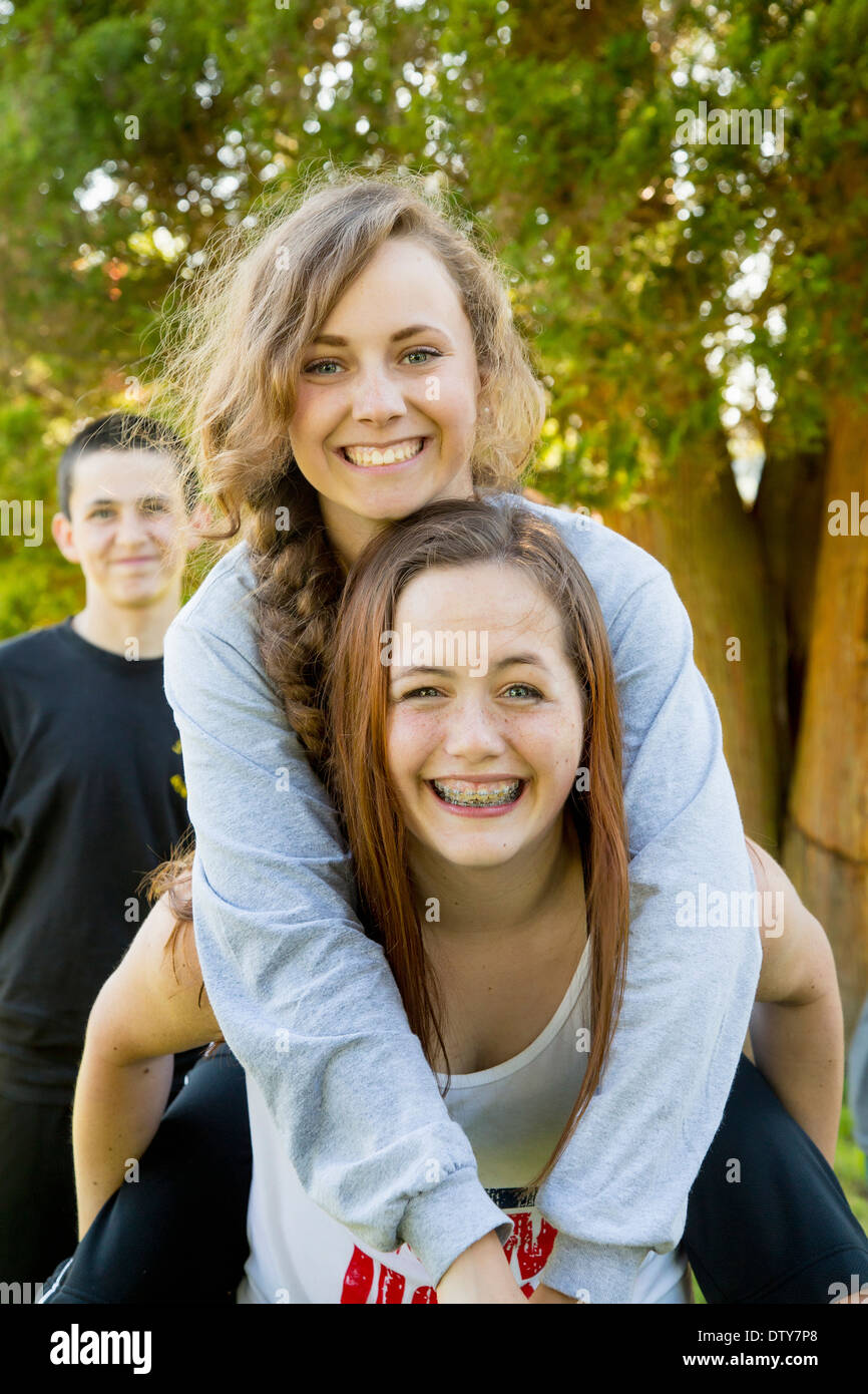 Caucasian ragazze adolescenti piggybacking in esterno Foto Stock