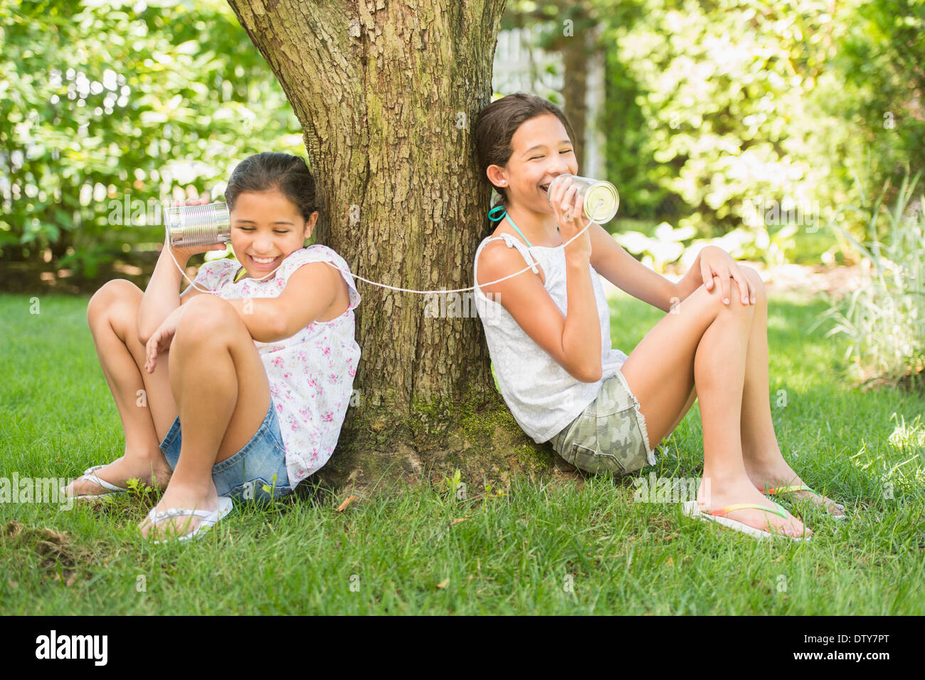 Razza mista ragazze parlando in barattolo di latta telefoni all'aperto Foto Stock
