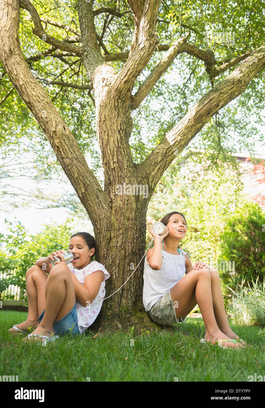 Razza mista ragazze parlando in barattolo di latta telefoni all'aperto Foto Stock