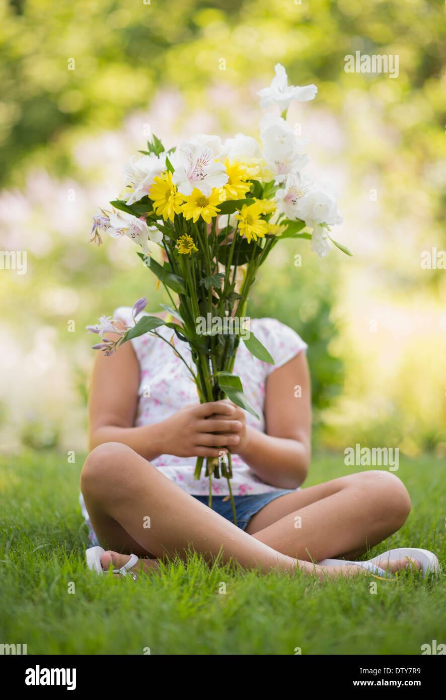 Razza mista ragazza con bouquet di fiori in erba Foto Stock