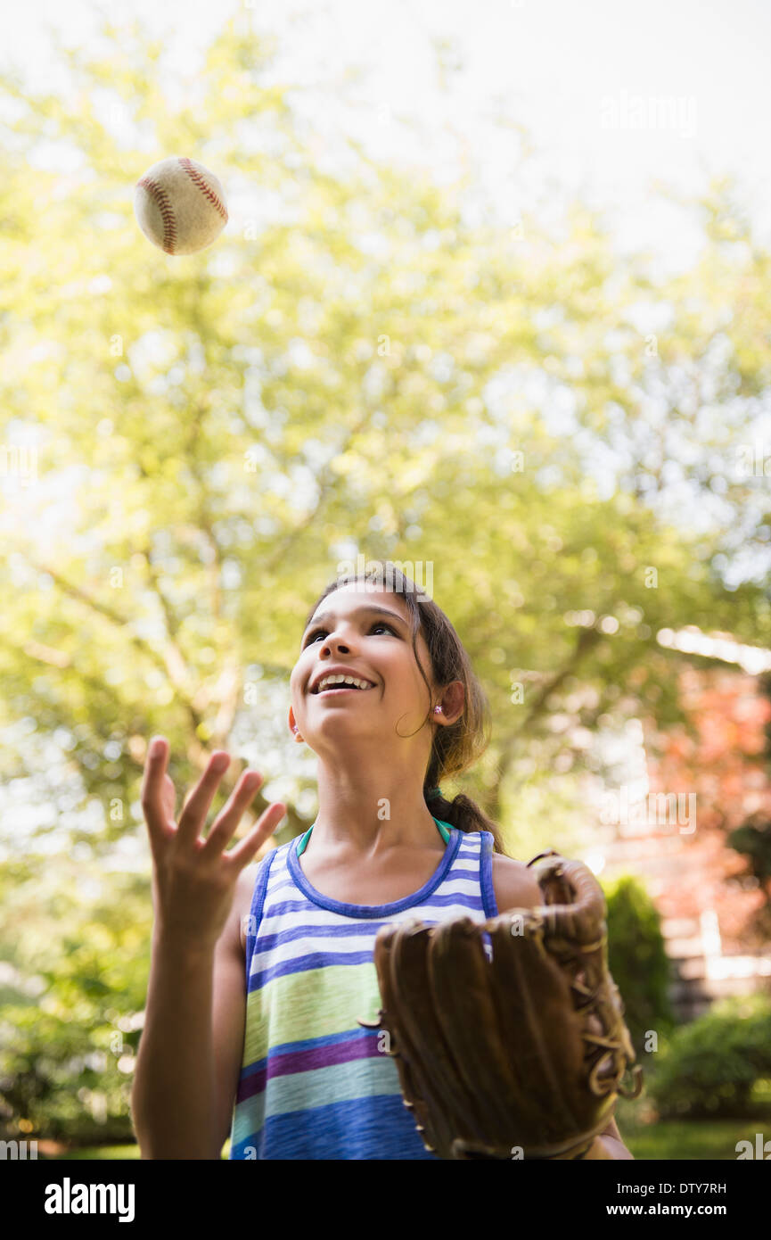 Razza mista ragazza che gioca con il baseball e mitt all'aperto Foto Stock