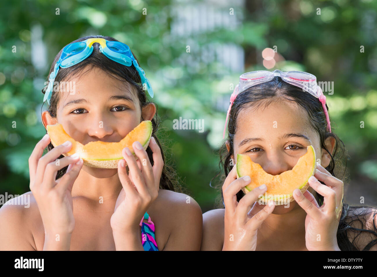 Razza mista ragazze giocare con cantaloupes all'aperto Foto Stock