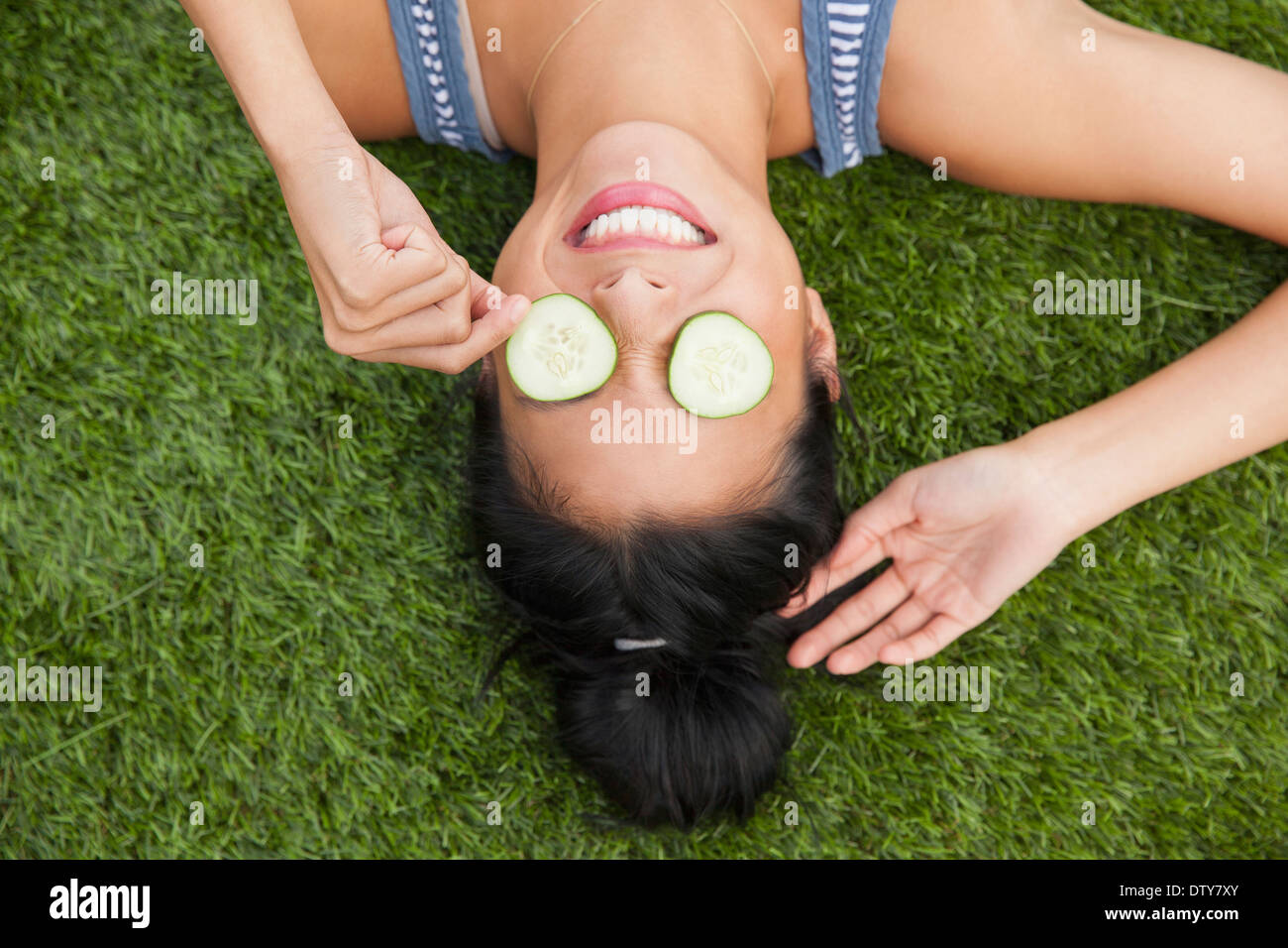 Donna cinese con cetrioli sugli occhi posa in erba Foto Stock