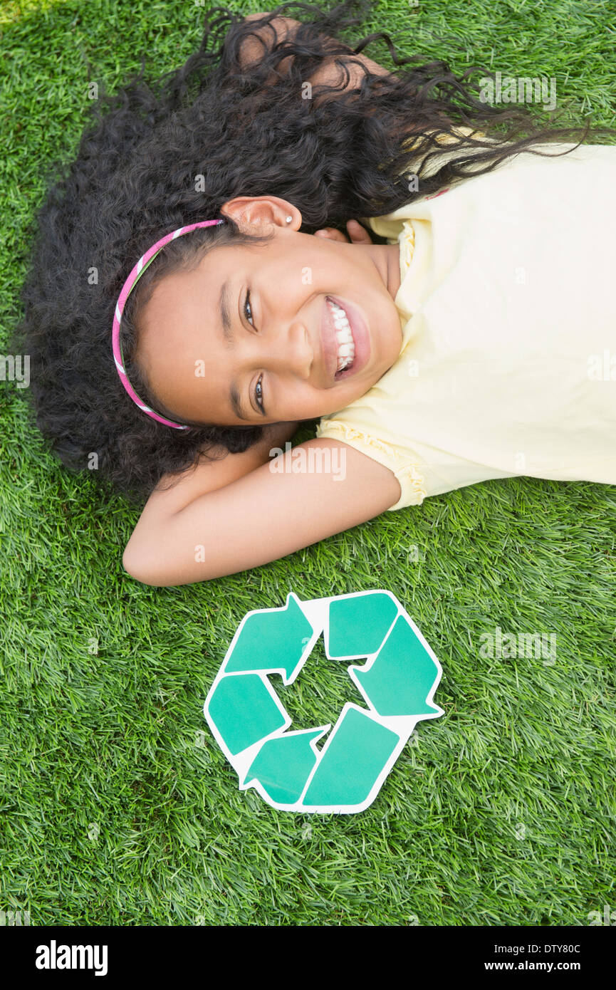 Razza mista ragazza con simbolo di riciclaggio in erba Foto Stock