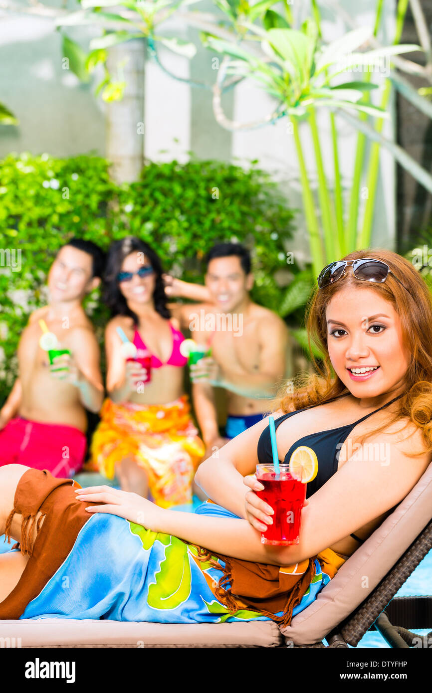 Amici asiatici partying e bere cocktail fantasia in hotel o club party in piscina Foto Stock