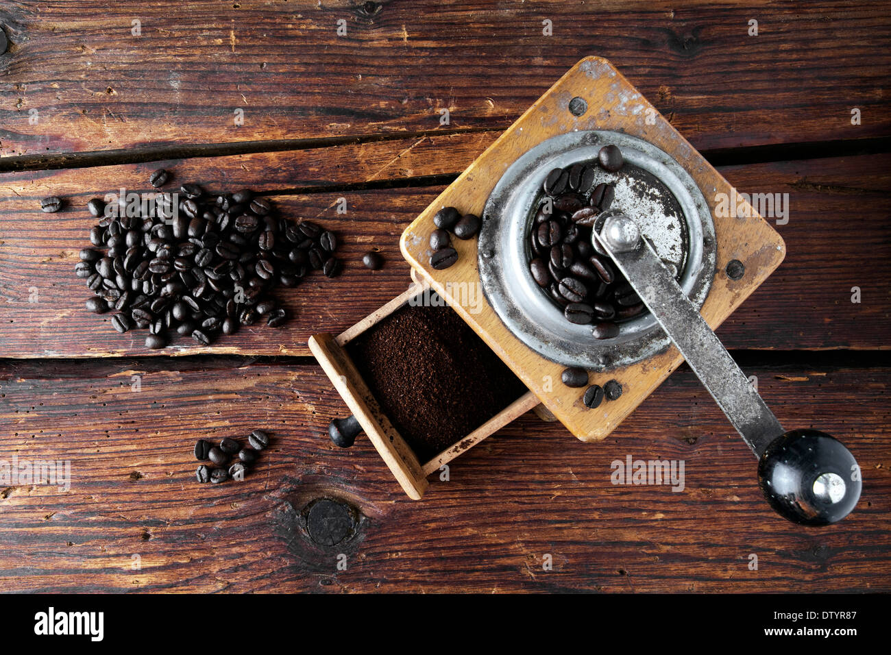 Vecchio macinino da caffè con i chicchi di caffè su una superficie in legno Foto Stock