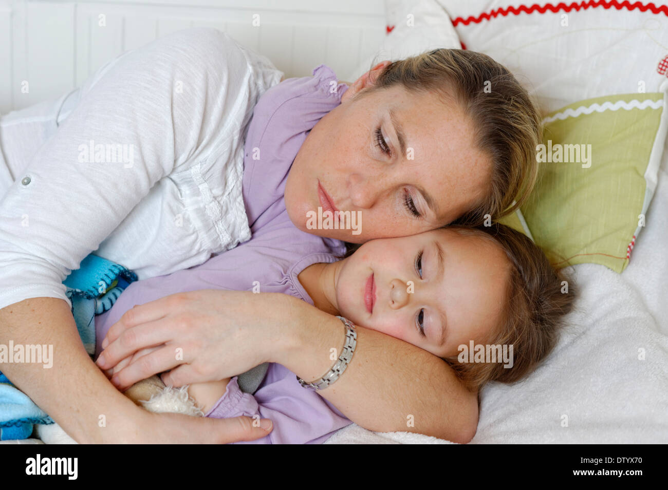 Madre e figlia coccole a letto, avvolgente Foto Stock