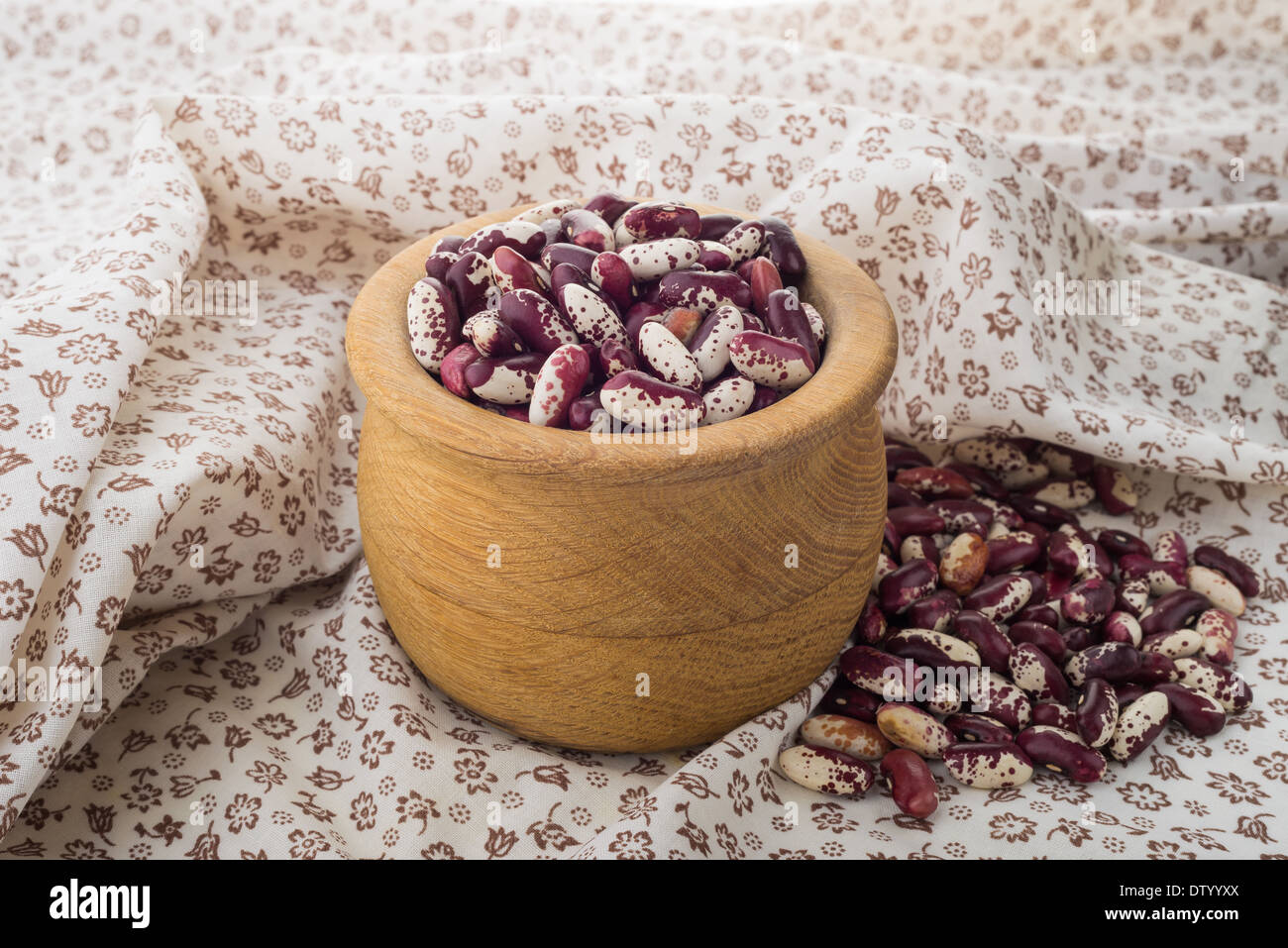 Red fagioli cannellini in una ciotola di legno su una tovaglia fioriscono Foto Stock