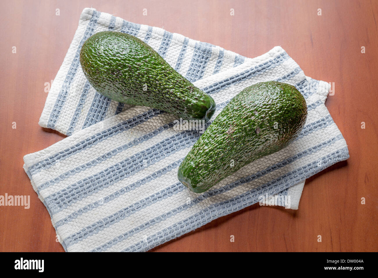 Due avocadi verde su bianco e blu di tovaglioli Foto Stock