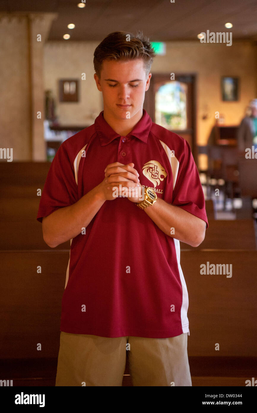 Un uniformata studente presso un privato Catholic High School in San Juan Capistrano, CA, prega nella scuola del cappella. Foto Stock