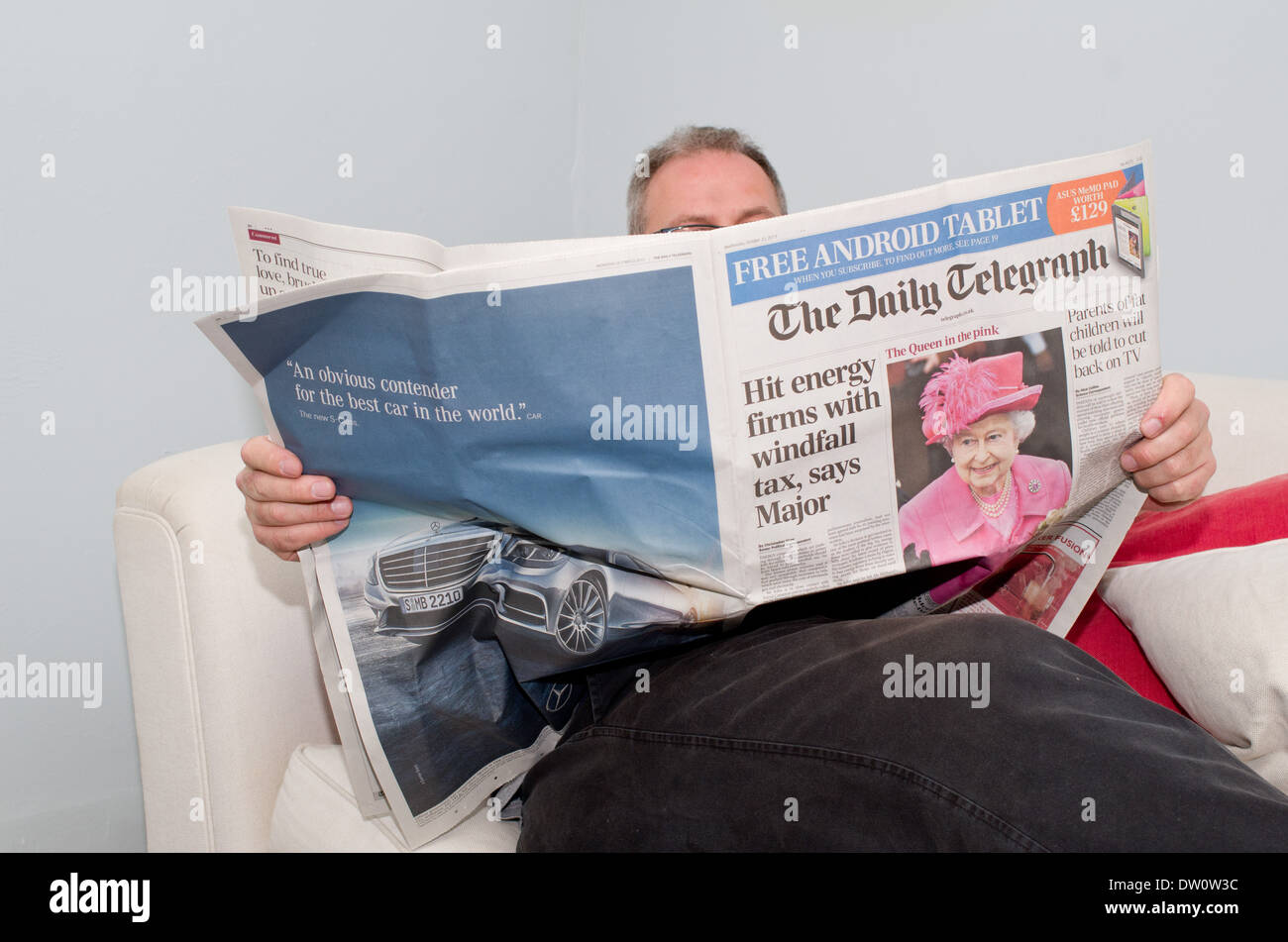 Uomo seduto a casa leggendo un giornale sulle ultime news Foto Stock