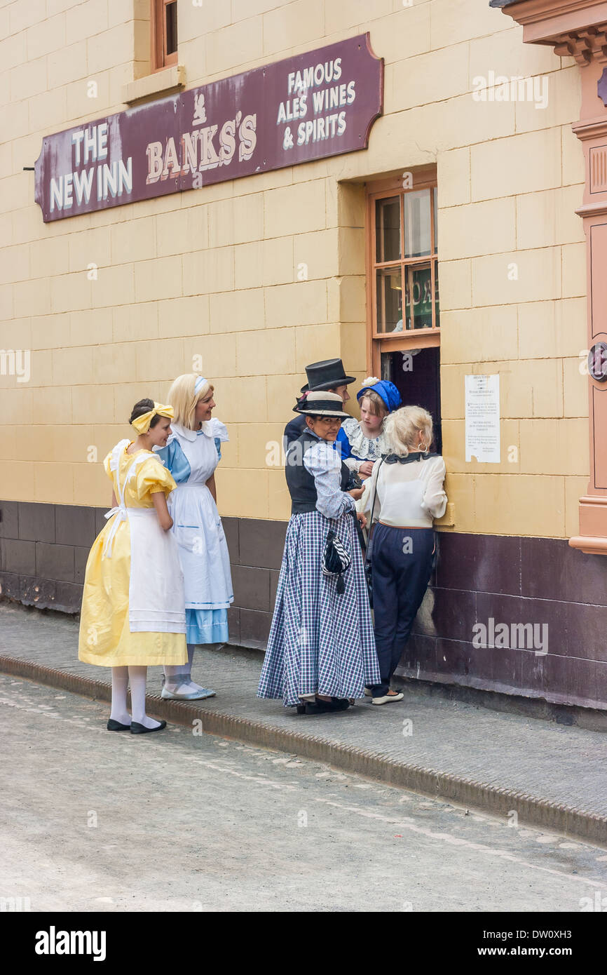 Persone vestite in costume in piedi al di fuori di una casa pubblica in chat come parte di Blists Hill città vittoriano attrazioni turistiche. Foto Stock