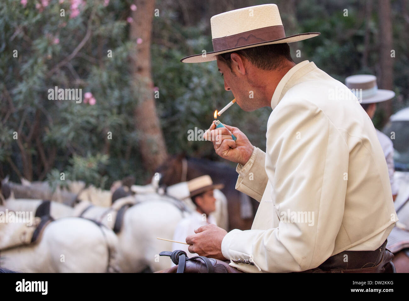 Un tubo flessibile di spagnolo rider illumina la sua sigaretta su un cavallo che indossano il tradizionale costume andaluso. Foto Stock