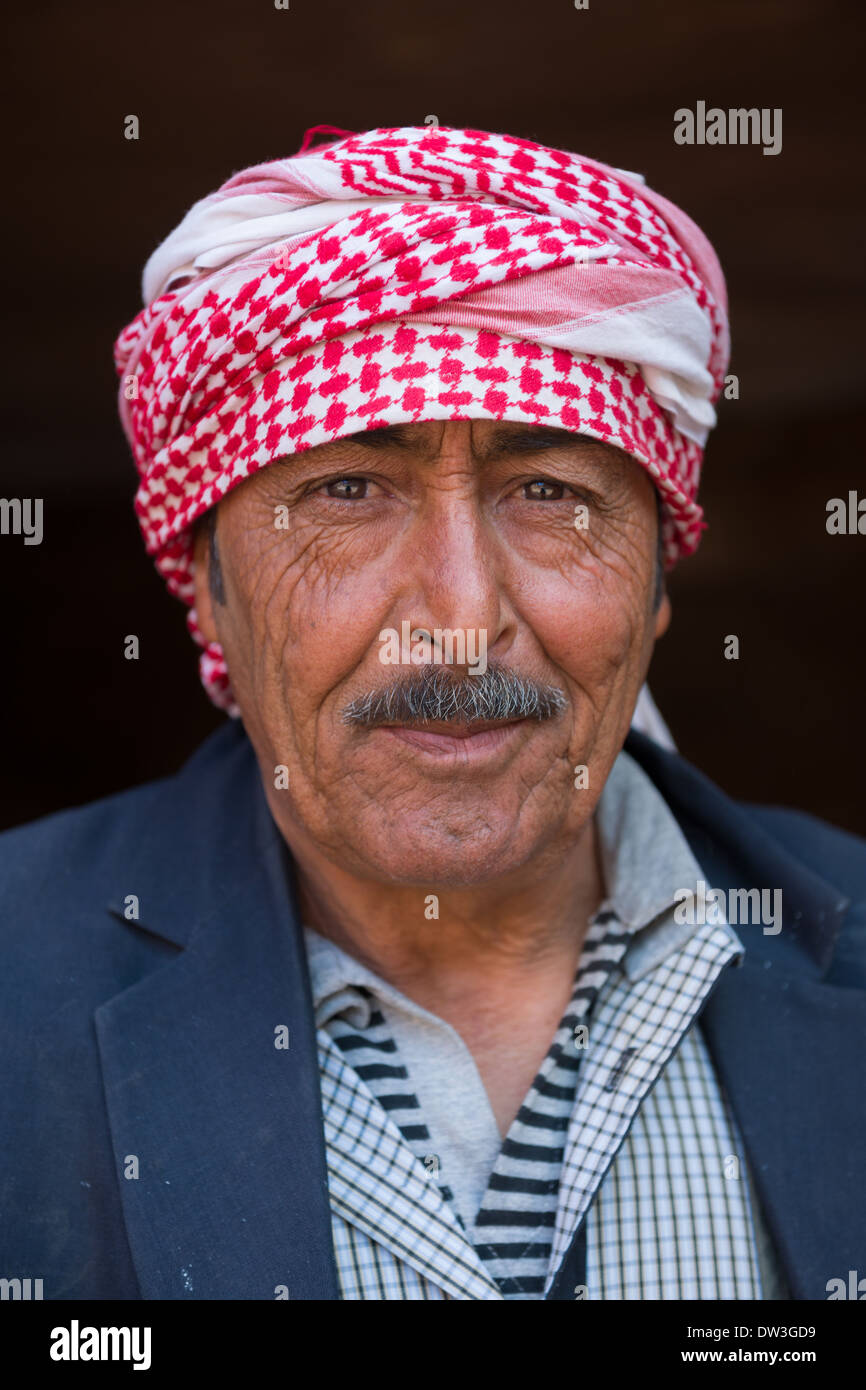 Salim, Beduino indossando un rosso Keffiyeh vendita monete tra le rovine di Petra, Giordania Foto Stock