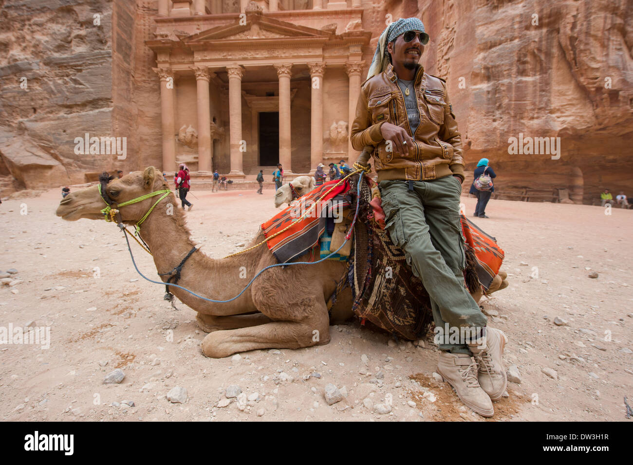 Giovane beduino appoggiata contro il suo cammello con Al Khazneh, (Tesoro) dietro, Petra, Giordania Foto Stock