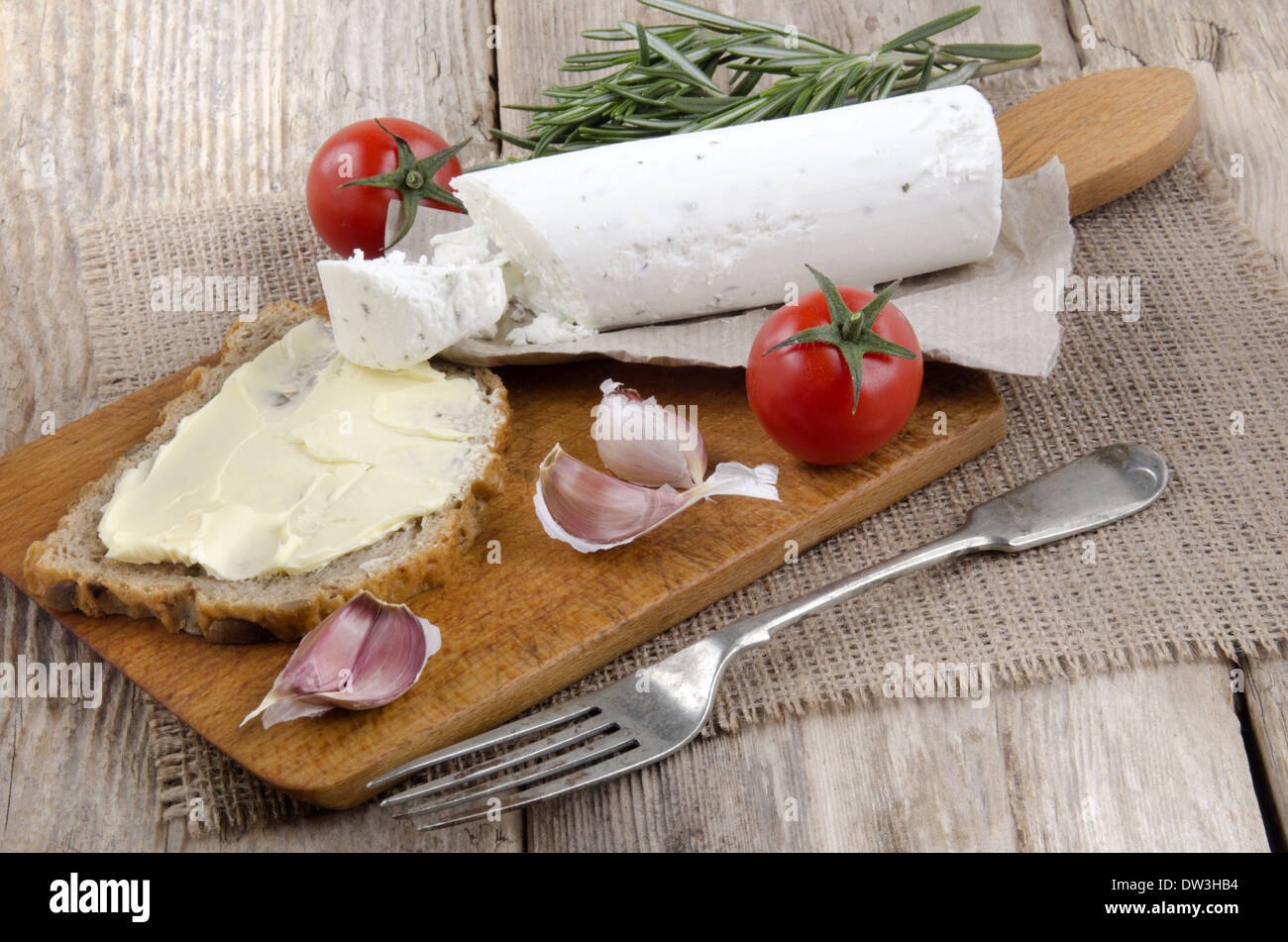 Tavola di legno con pane morbido formaggio di capra e pomodoro Foto Stock