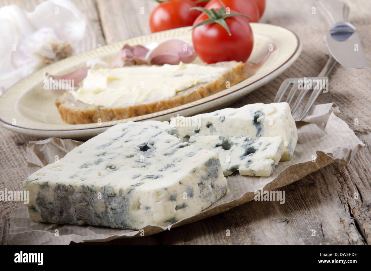 Piastra con pane e pomodoro, aglio e francese di formaggio blu su carta marrone Foto Stock